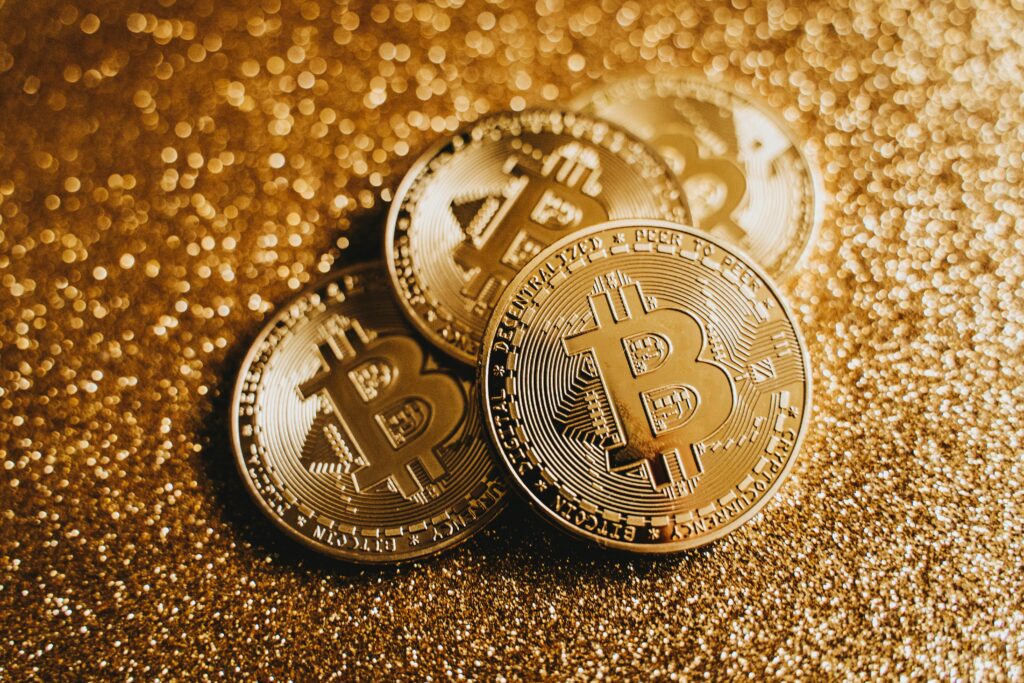 Close-up of golden Bitcoin coins on a sparkling, glitter-covered surface highlighting cryptocurrency wealth.
